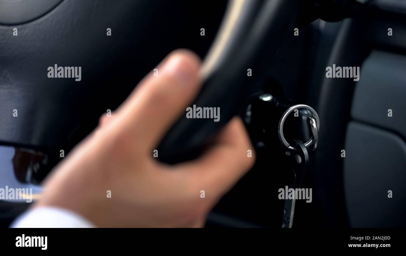Man driving car, holding hand on wheel, close up on keys