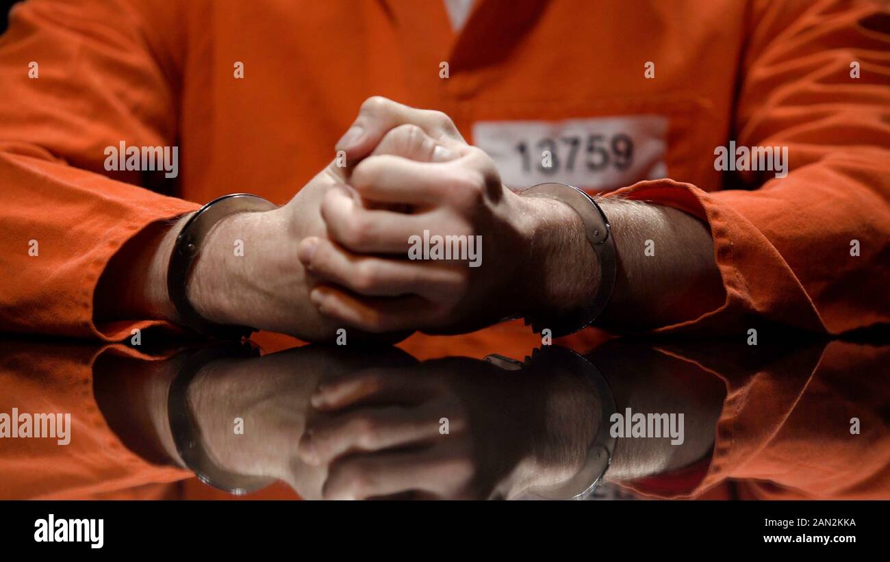 Prisoner in handcuffs clenching fists, denying quilt, interrogation room Stock Photo