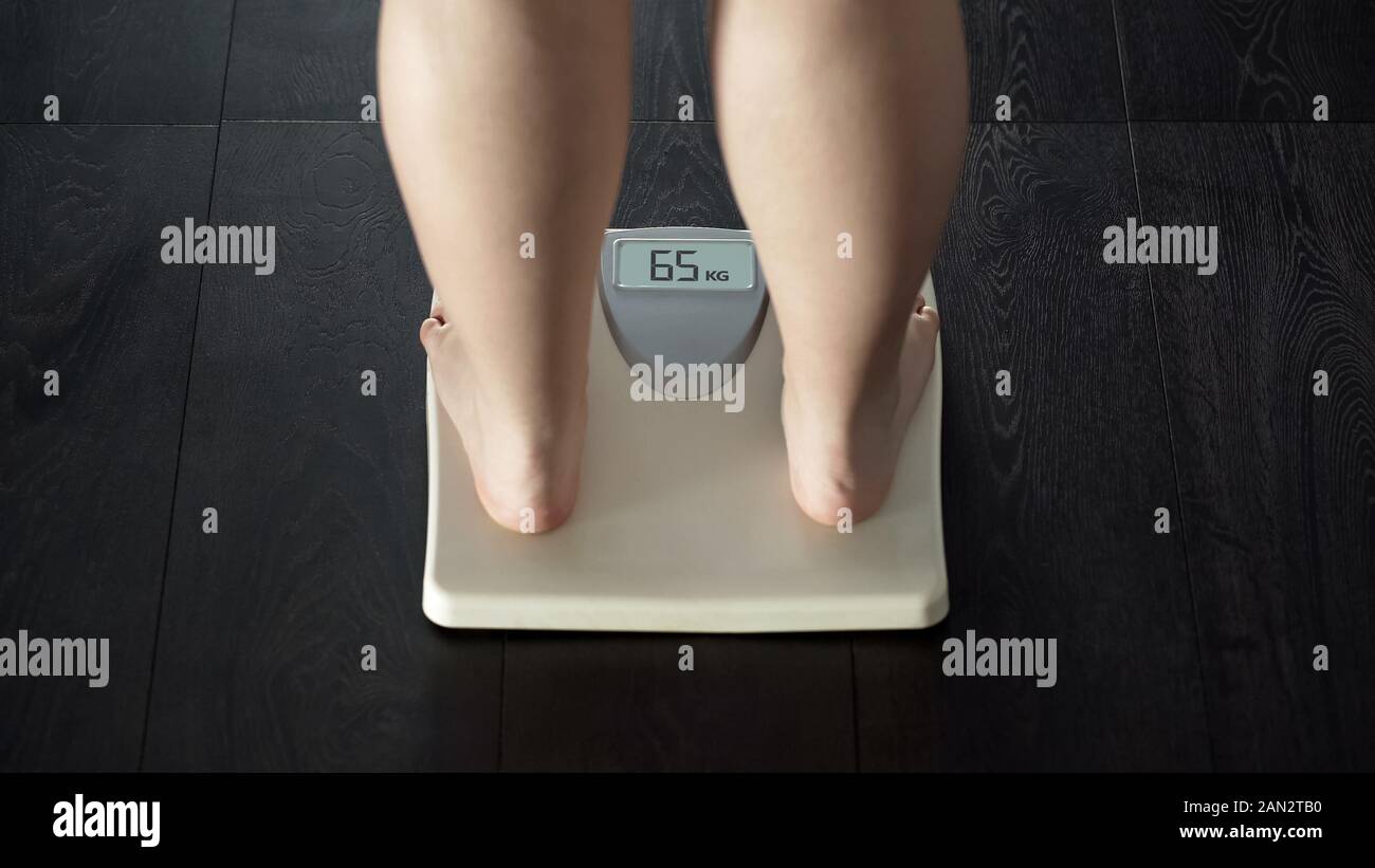 Female measuring body weight on scales, healthy dieting, balanced nutrition Stock Photo