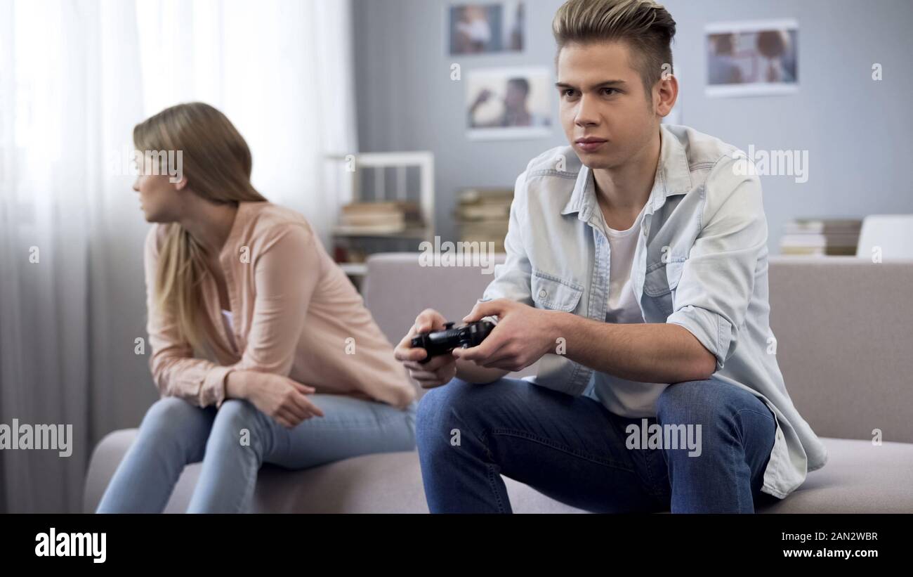 Offended girl turned away from boyfriend who indifferently playing
