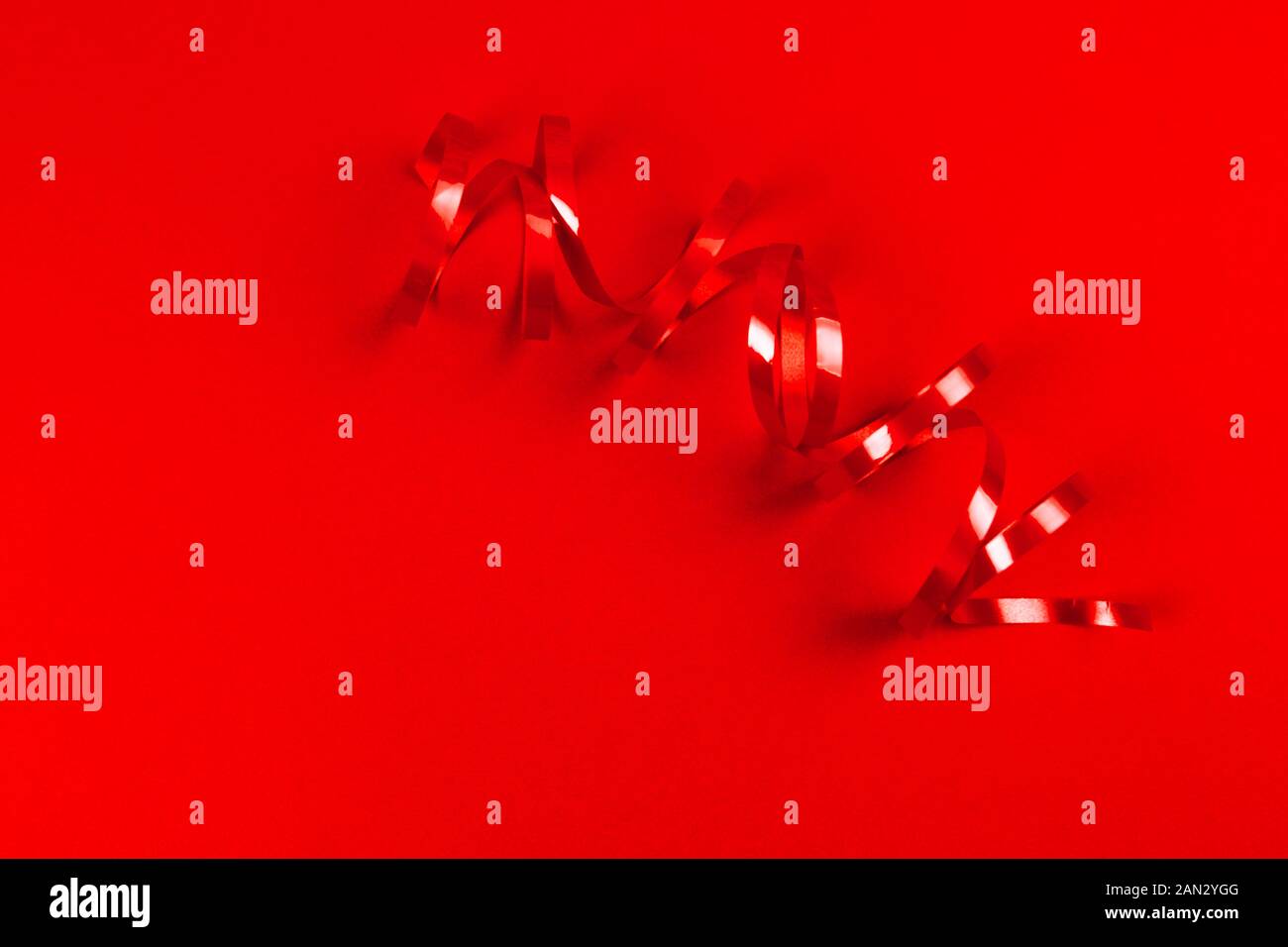 Red ribbon roll on red background. Hollyday and party concept. Stock Photo