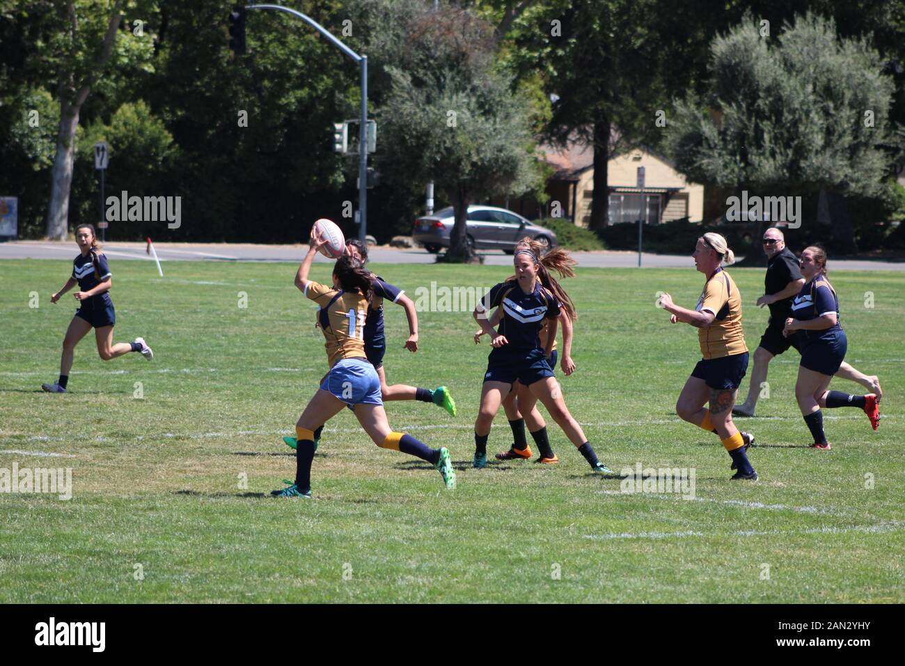 College aged women playing rugby in an open field, passing the ball and ...