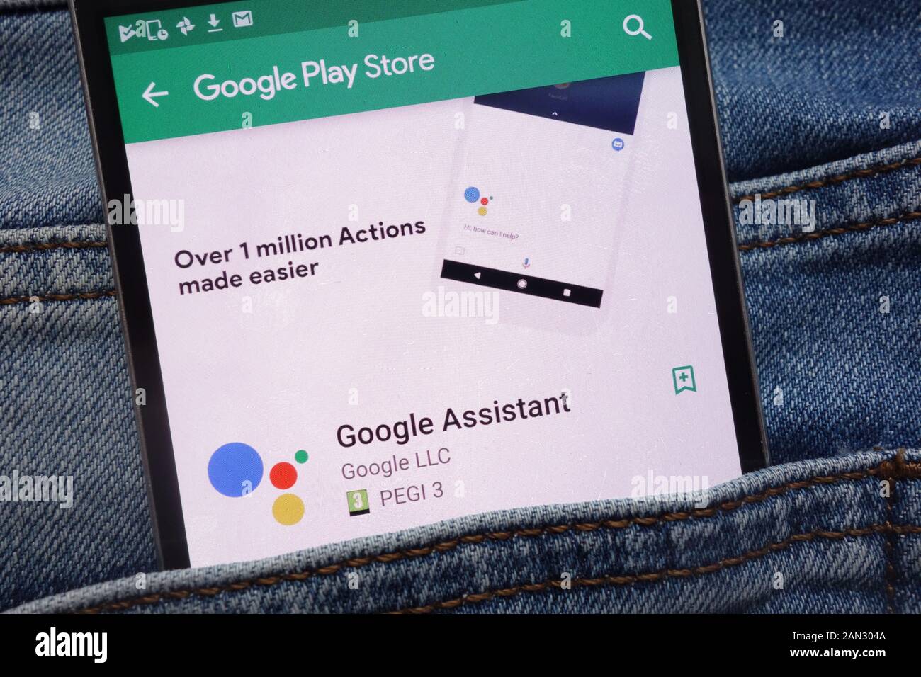 Google Assistant app on Google Play Store website displayed on smartphone hidden in jeans pocket Stock Photo