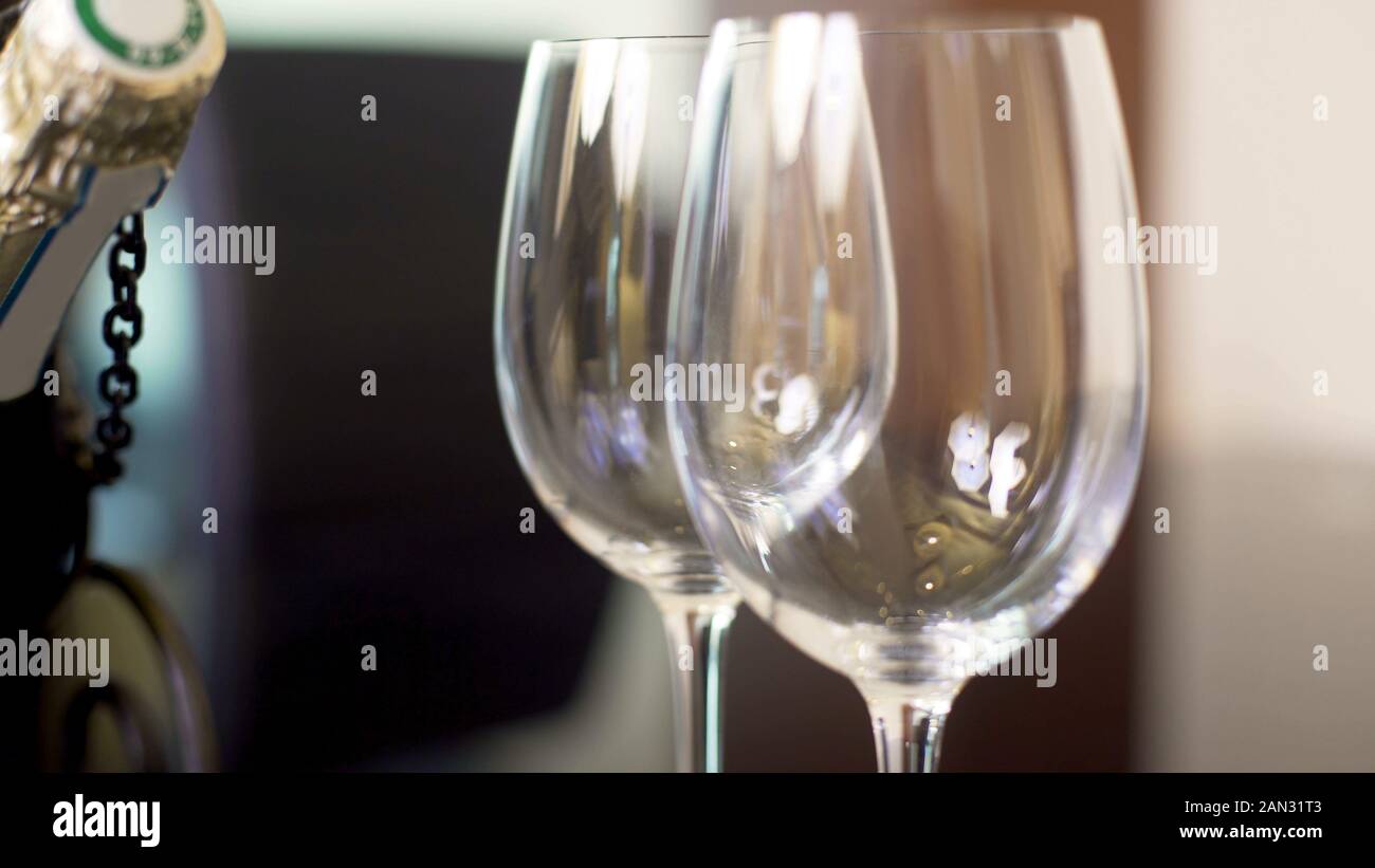 Two empty wineglasses and champagne bottle standing on table, celebration Stock Photo