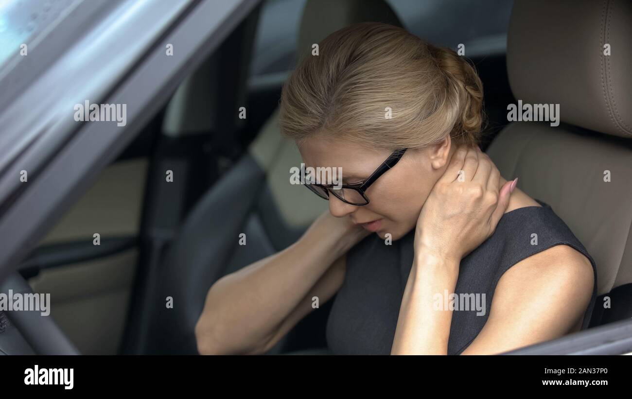 Exhausted woman feeling neck pain, sitting in automobile, spinal problem, health Stock Photo