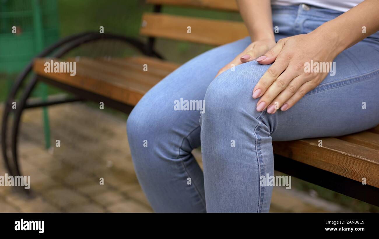 Woman feeling sharp knee pain while getting up from bench, painful