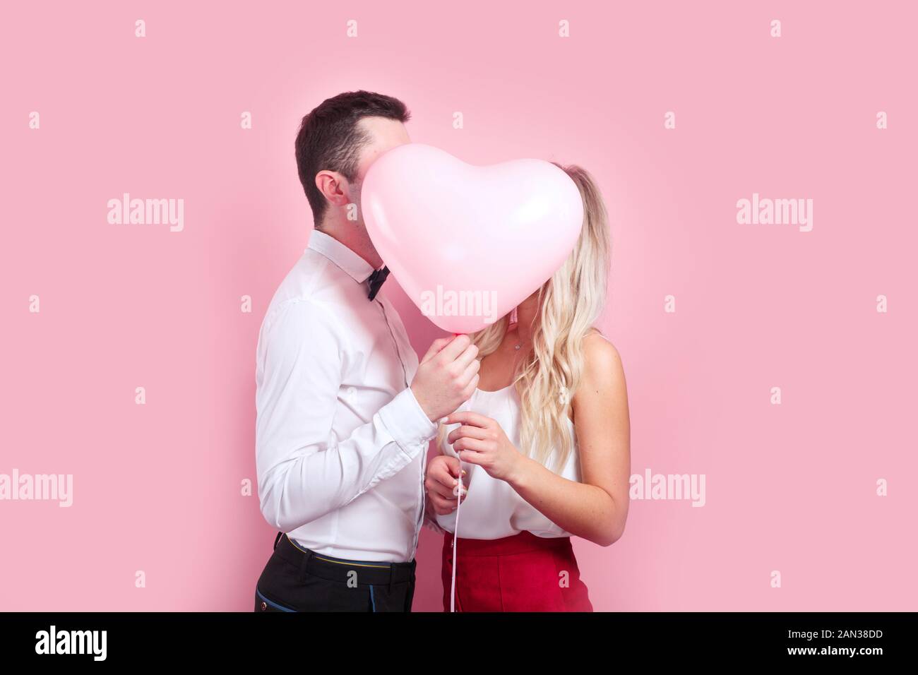 Couple holding heart shaped air balloon and kissing Stock Photo - Alamy
