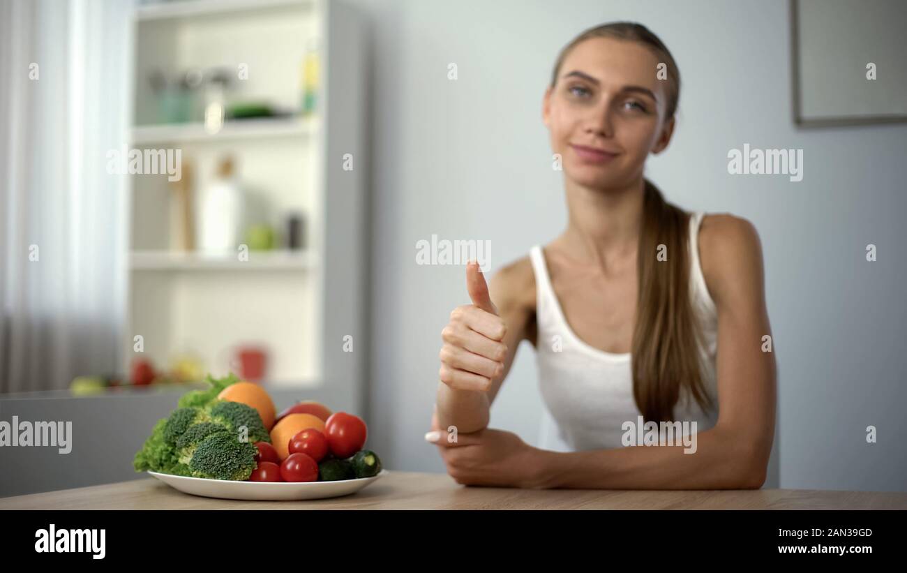 Skinny girl showing thumbs up, recommending vegetables, health, proper nutrition Stock Photo
