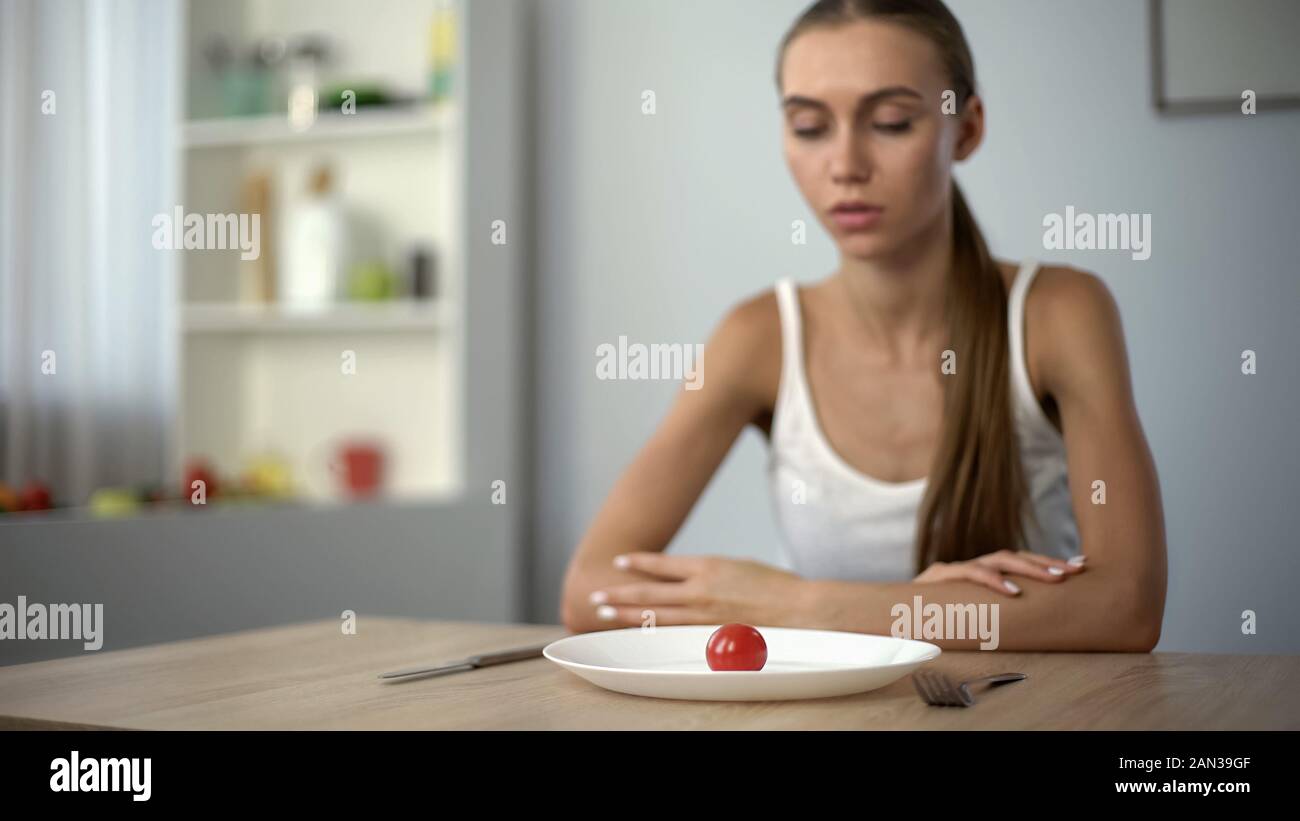 Underweight woman looking at small portion of meal, exhausted body, severe diets Stock Photo