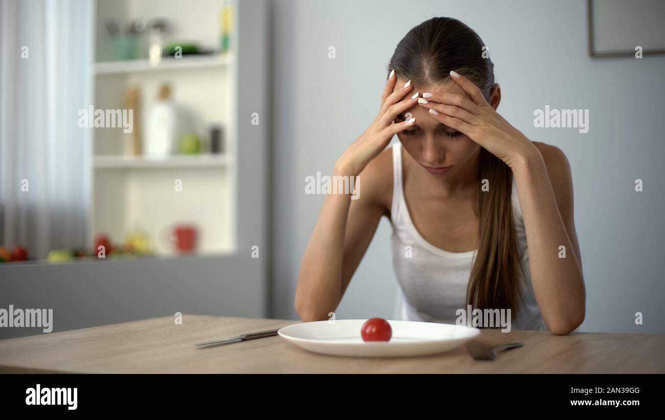 Anorexic girl feels dizzy, depleted by severe diets, exhausted body, starvation Stock Photo