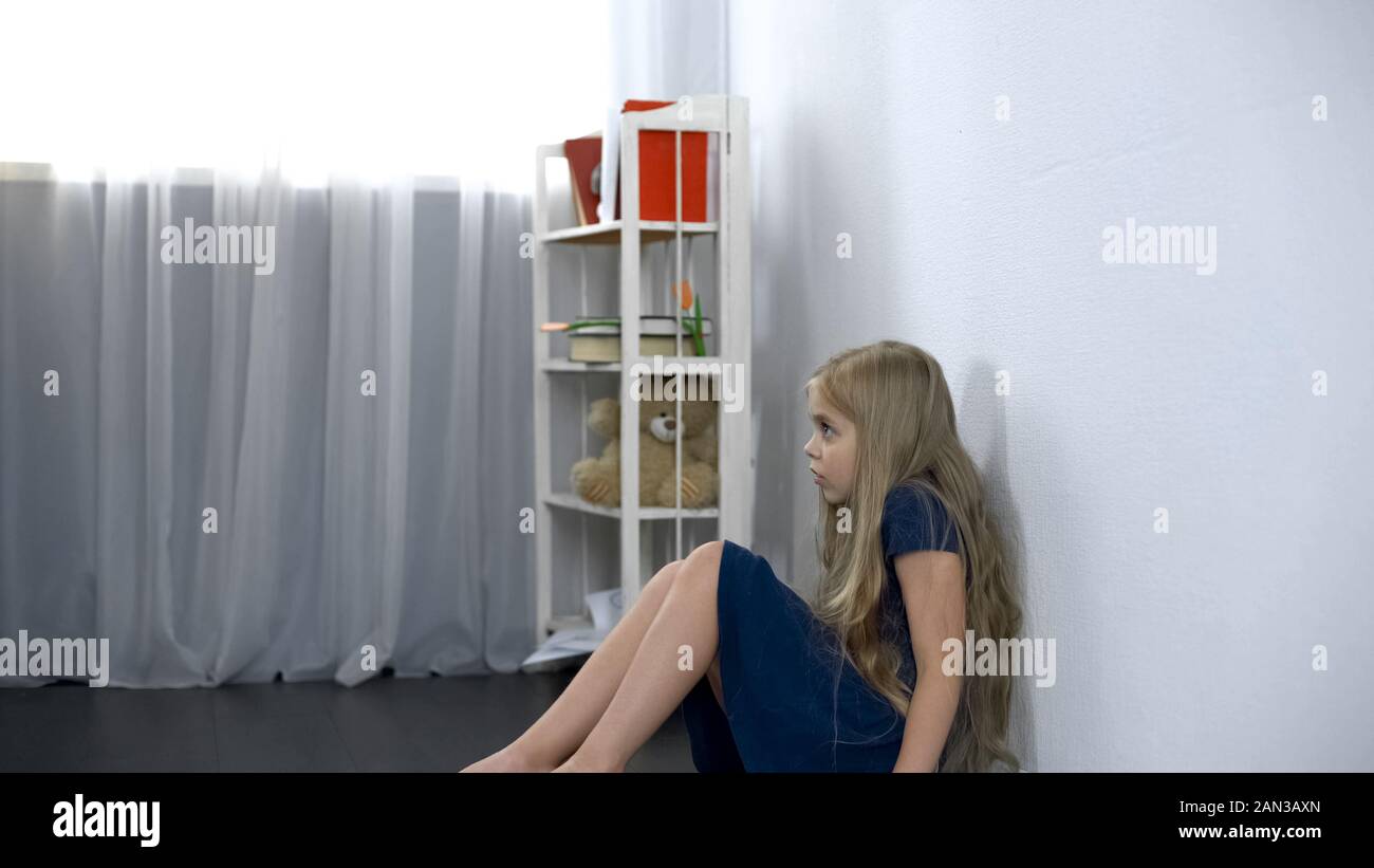 Scared girl sitting on floor, child kidnapping, emotional stress, hostage Stock Photo