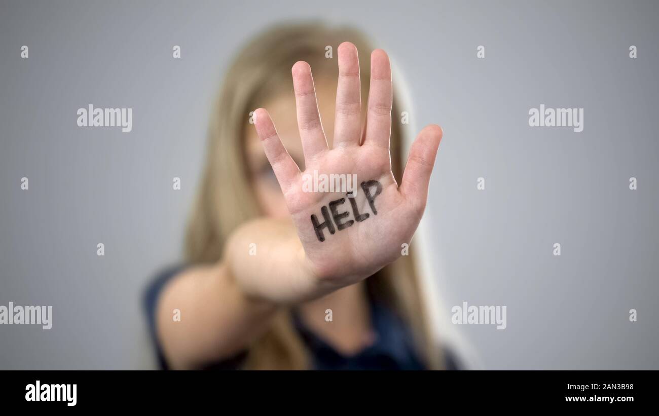 Help inscription on palm of sad little girl, protection of childrens rights Stock Photo