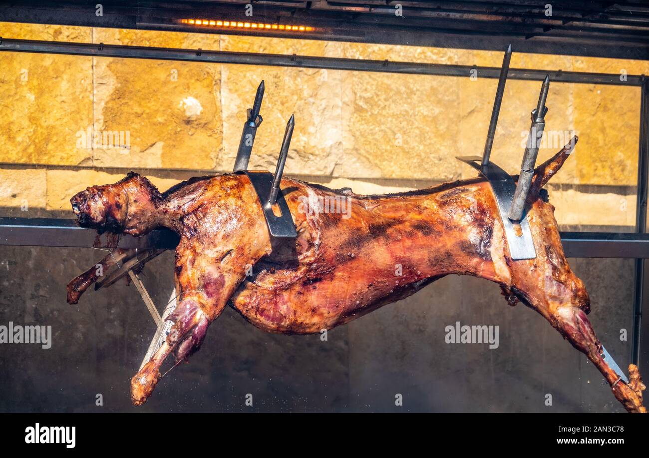 The carcass of a lamb is roasted on a spit. Closeup carcass of a sheep