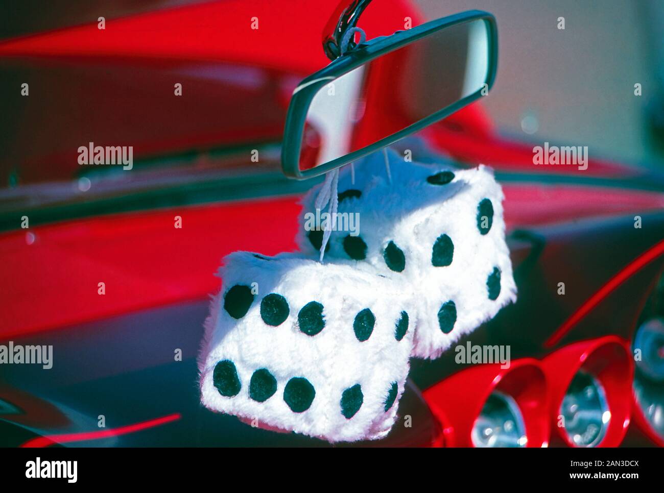 Fuzzy dice hanging from the rear view mirror of a vintage car Stock Photo