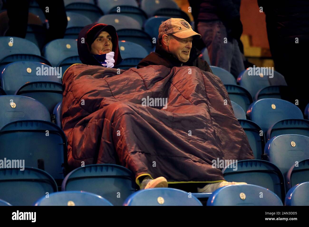 Cardiff City fans keep warm in the stands during the FA Cup third round replay match at Brunton Park, Carlisle. Stock Photo