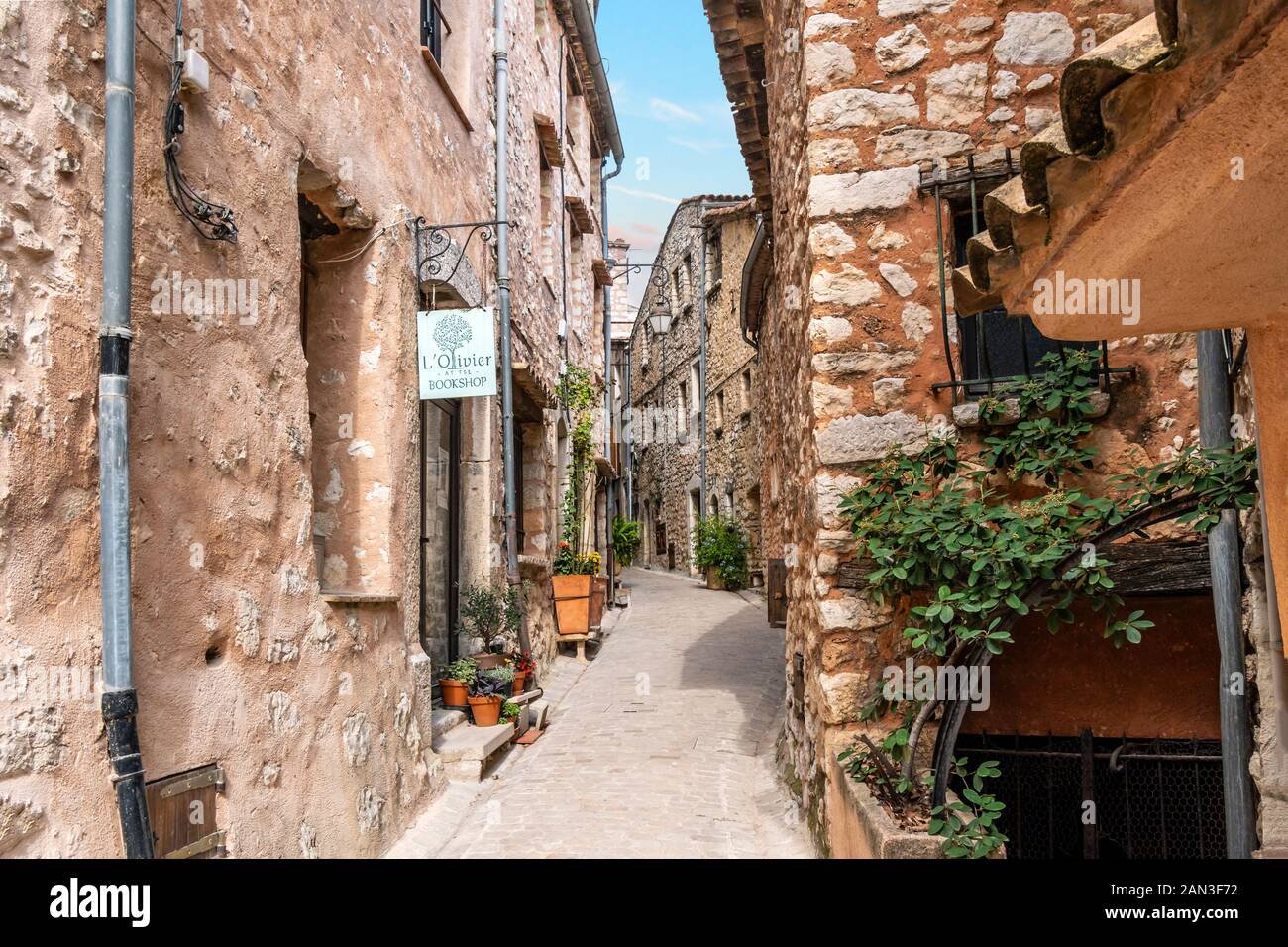 One of the many narrow alleys filled with homes and shops in the medieval walled village of Tourrettes Sur Loup in the Alpes-Maritimes area of France. Stock Photo