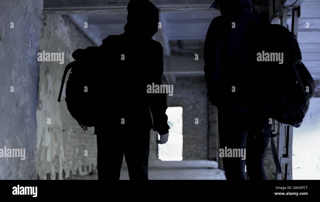 Criminals wearing black walking in abandoned house, crime planning, conspiracy Stock Photo
