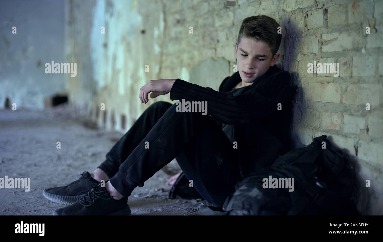 Teen boy sitting in abandoned building, escaped from dysfunctional family Stock Photo
