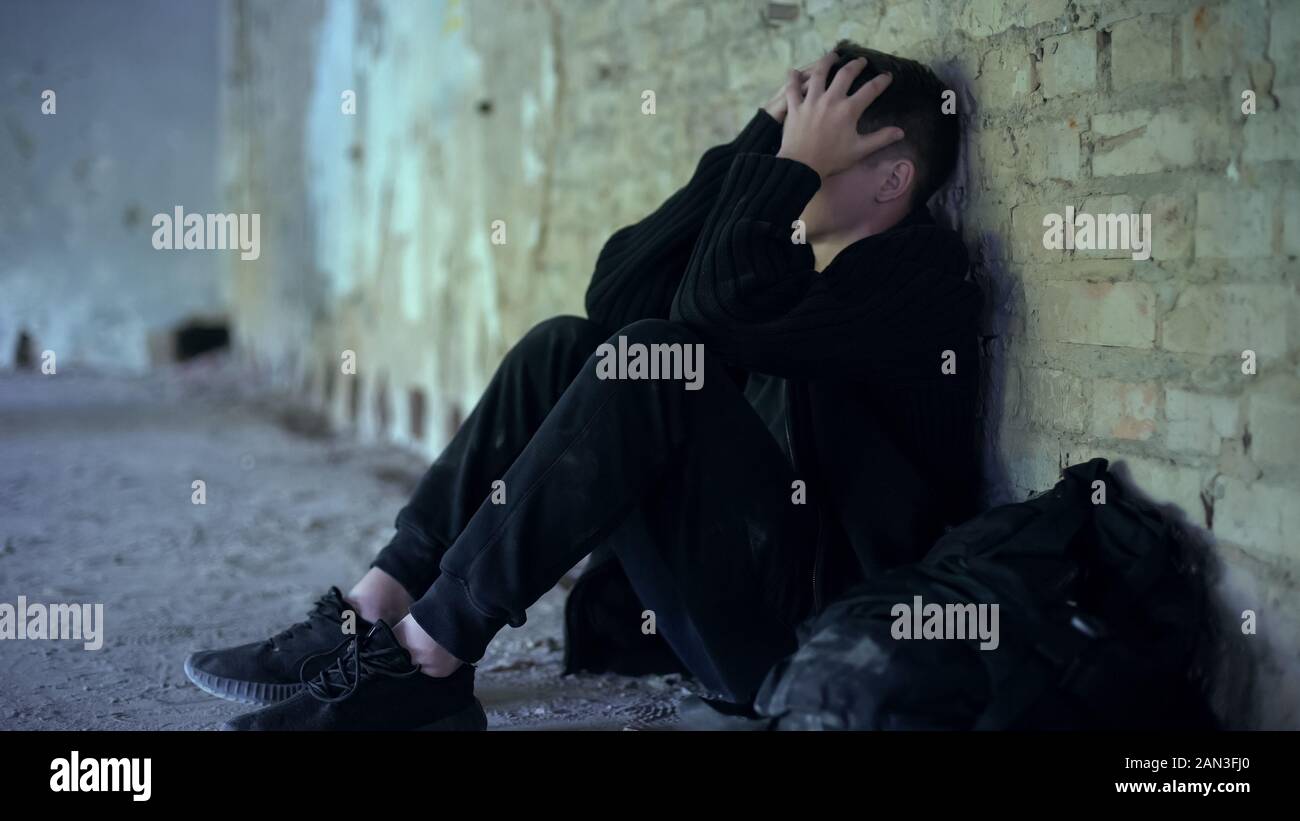 Teenage boy hiding in abandoned building, escaped from dysfunctional family Stock Photo