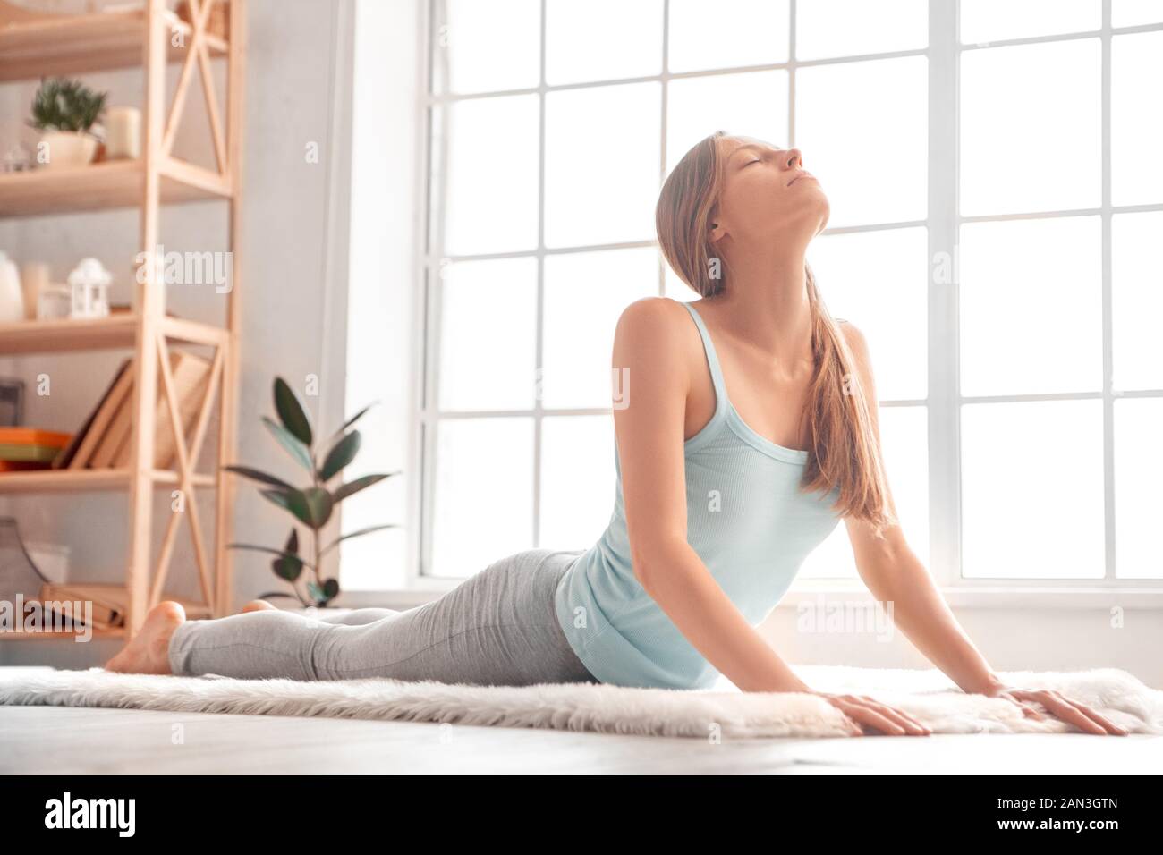 Weekend. Woman exercise at home on carpet stretching back peaceful Stock Photo