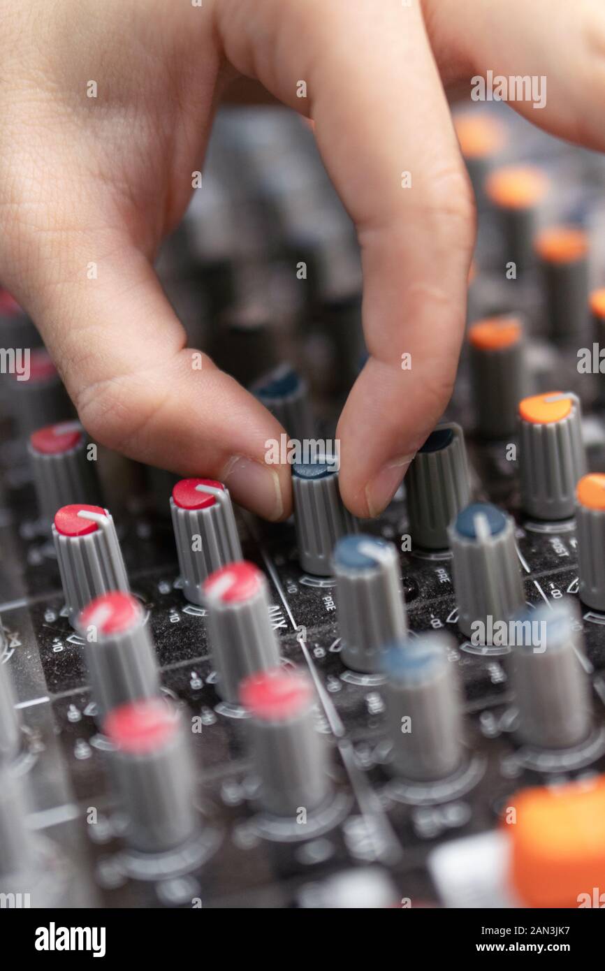 Closeup of a mixing console, hand equalizing audio channels