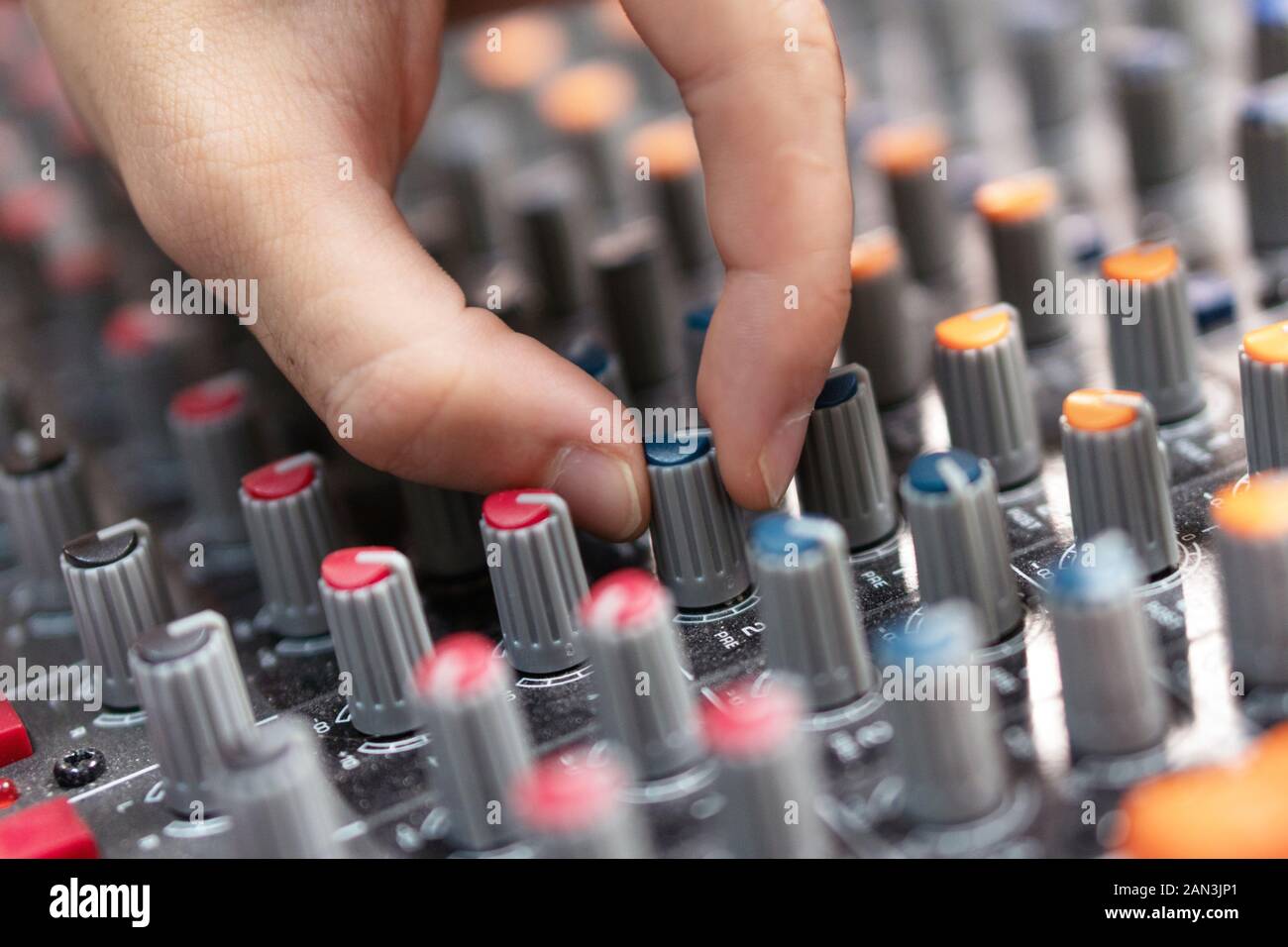 Closeup of a mixing console, hand equalizing audio channels
