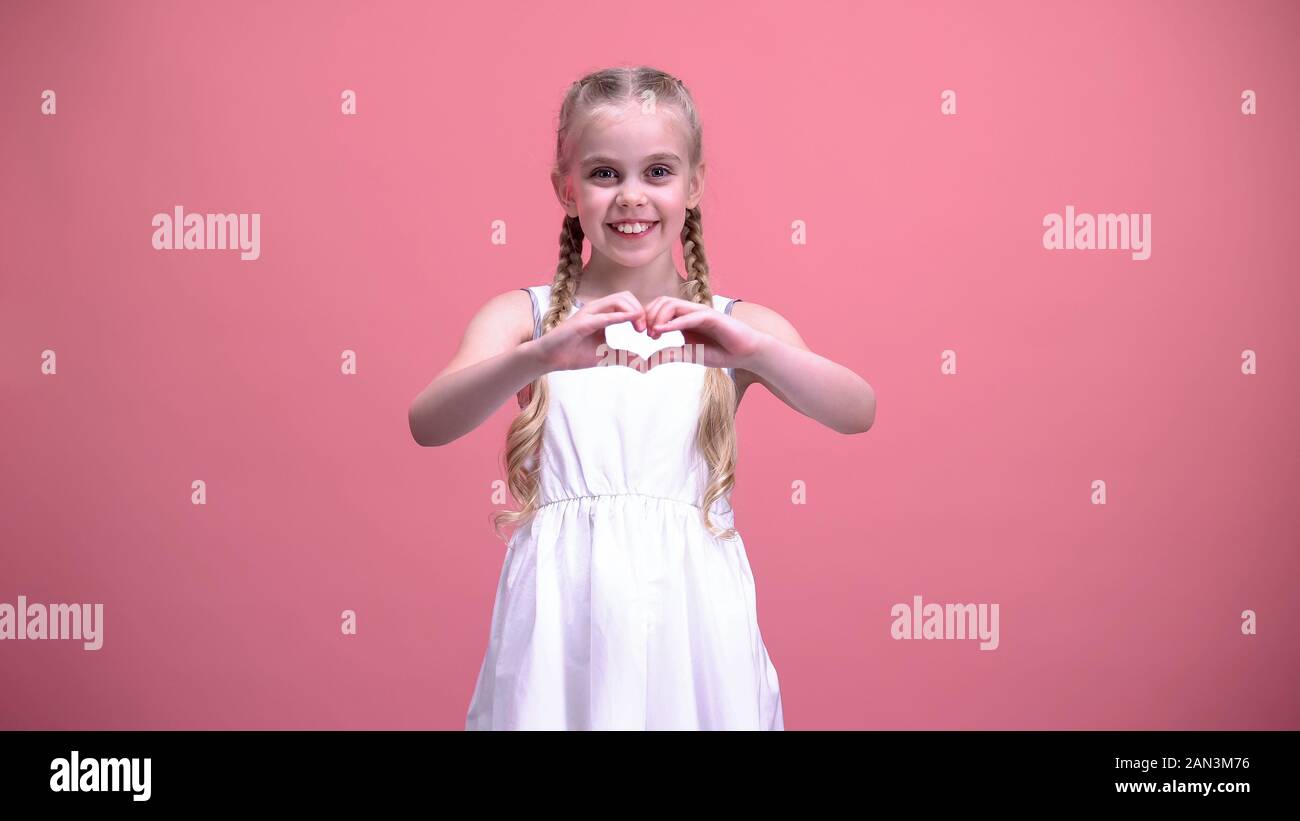 Cute little girl with braids showing heart gesture, charity, children adoption Stock Photo