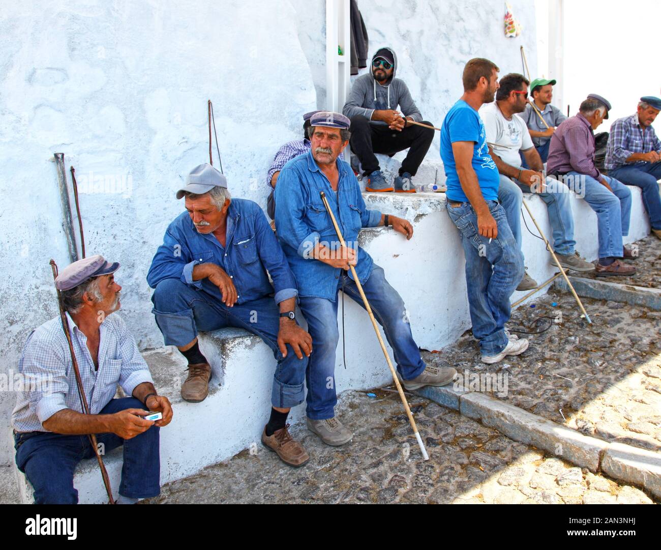Local guides wait for customers to ride mules down the steep cobblestone path from Fira town to the port in Santorini Greece. Stock Photo