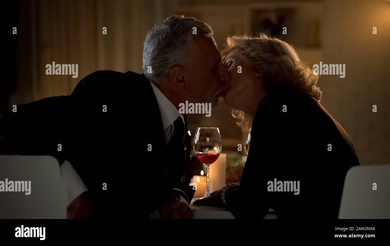Loving couple kissing in restaurant, celebrating anniversary date, togetherness Stock Photo