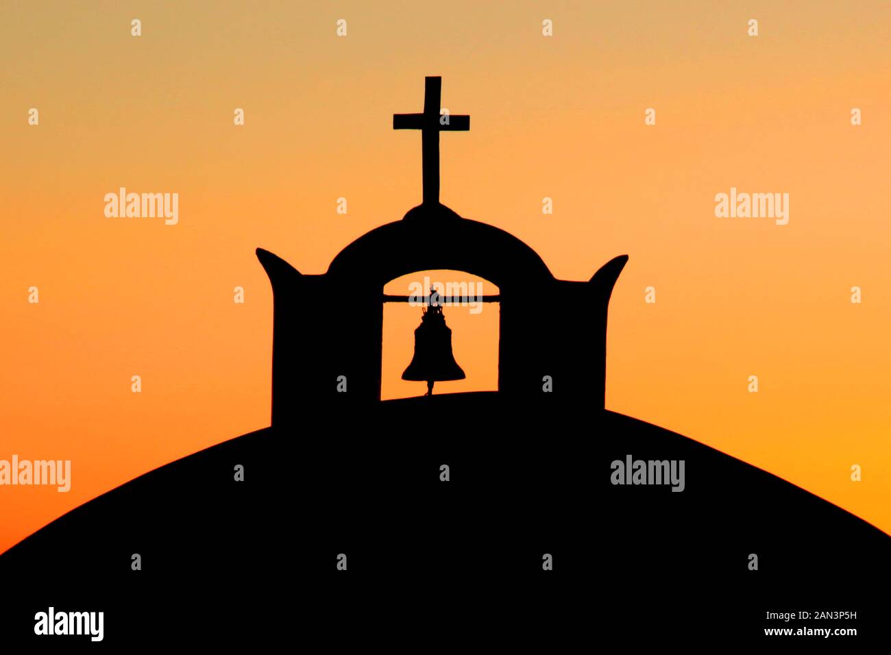 A church dome with bell and religious cross in the town of Oia in Santorini, Greece. Stock Photo
