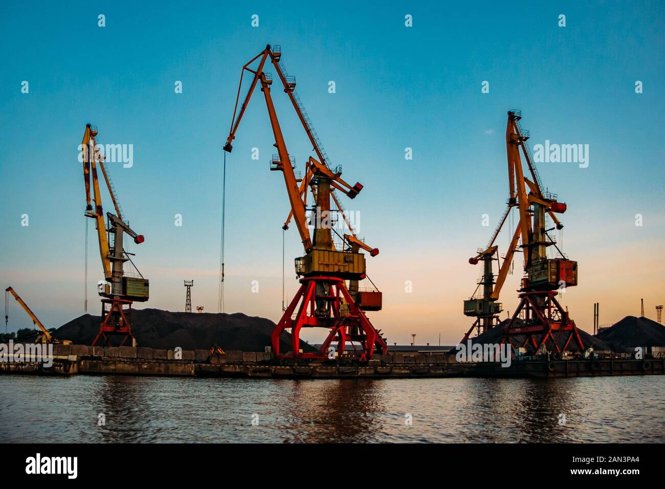 Harbor cargo cranes on sunset sky background Stock Photo - Alamy
