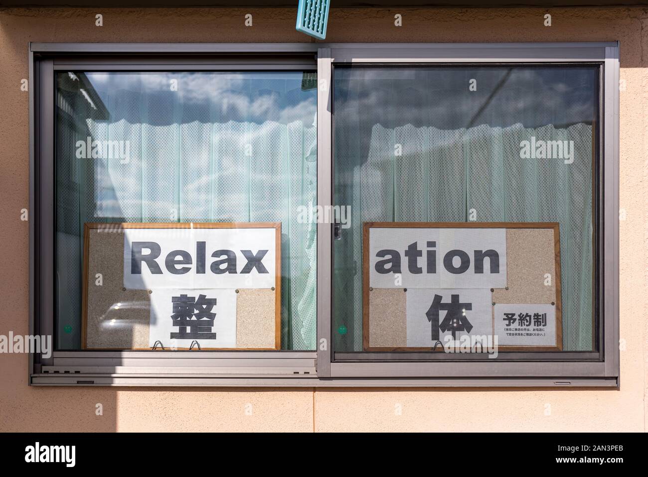'Relax' 'ation' – relaxation sign split across two windows; Japanese and English Stock Photo