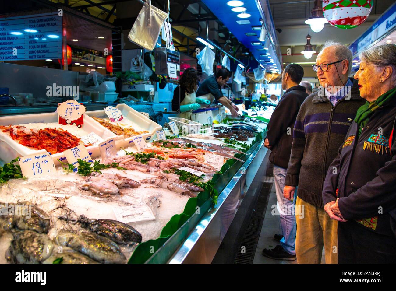 Elderly couple shopping for calamari and seafood at a stall in Mercat de l'Olivar, Palma, Mallorca, Spain Stock Photo