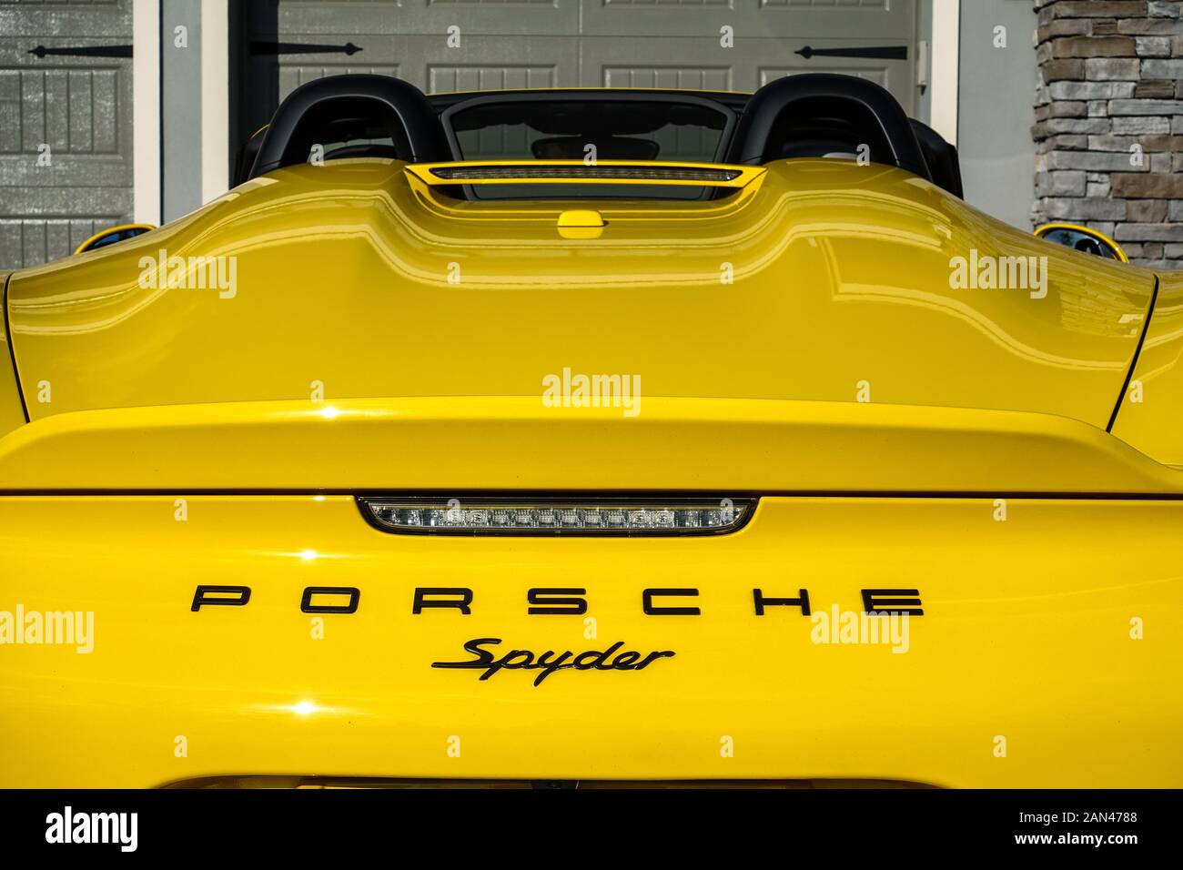 Orlando, FL/USA-1/15/20: The rearend of a yellow Porsche Spyder sitting in front of a home. Stock Photo