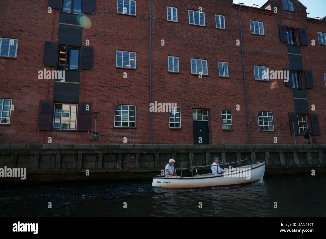 Two people in a boat in front of a brick building in Copenhagen, Denmark Stock Photo