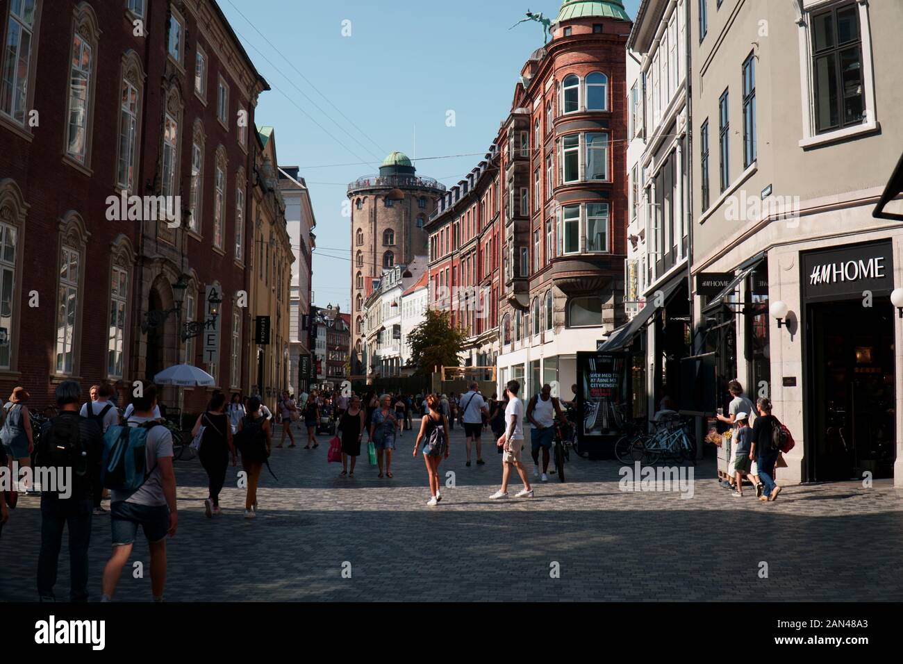 A busy street in central Copenhagen in summer, with the Round Tower seen in the distance Stock Photo