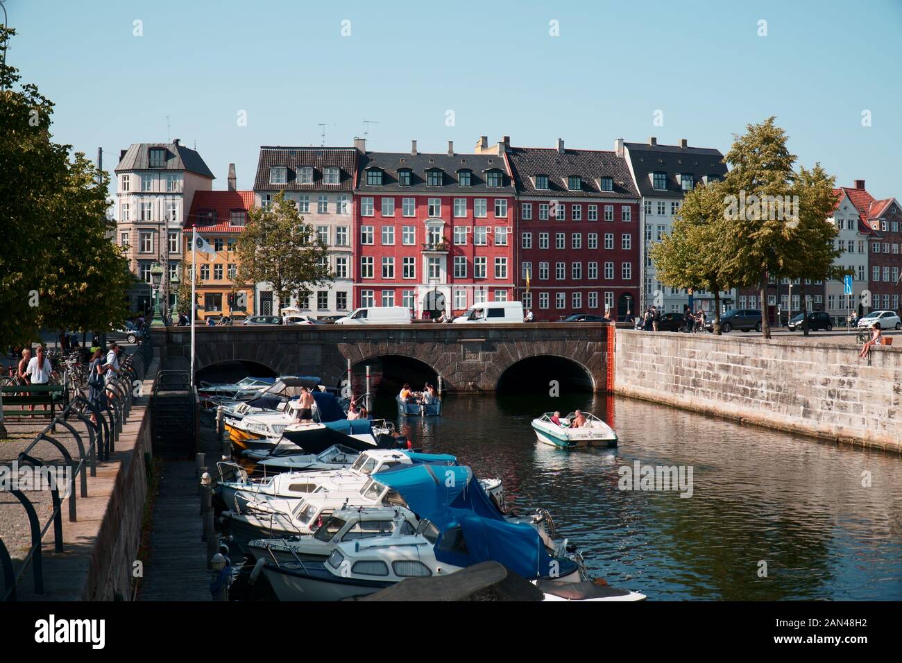 Boats docked in a canal in Copenhagen, Denmark, looking out to colourful houses Stock Photo