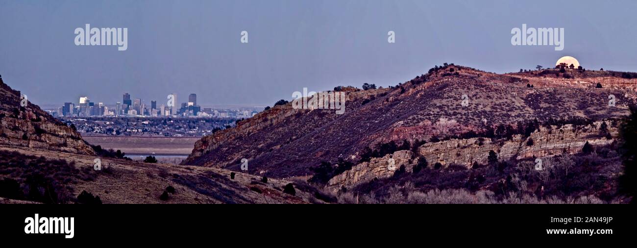 Denver Colorado's skyline viewed from the west looking north east as the rising moon peeks over nearby foothills. Stock Photo