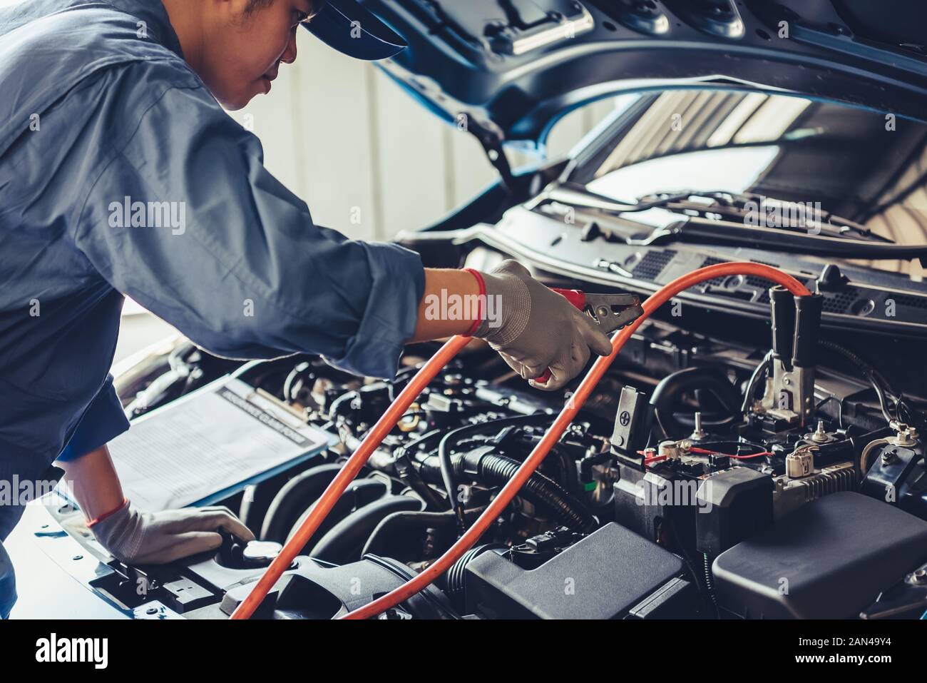 Car mechanic holding battery electricity trough cables jumper and