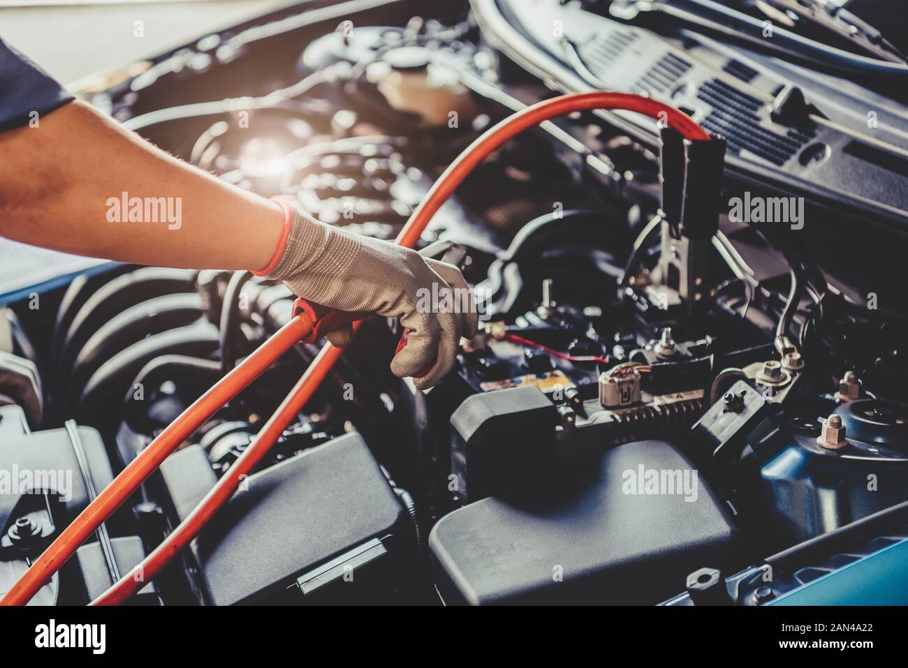 Car mechanic holding battery electricity trough cables jumper and