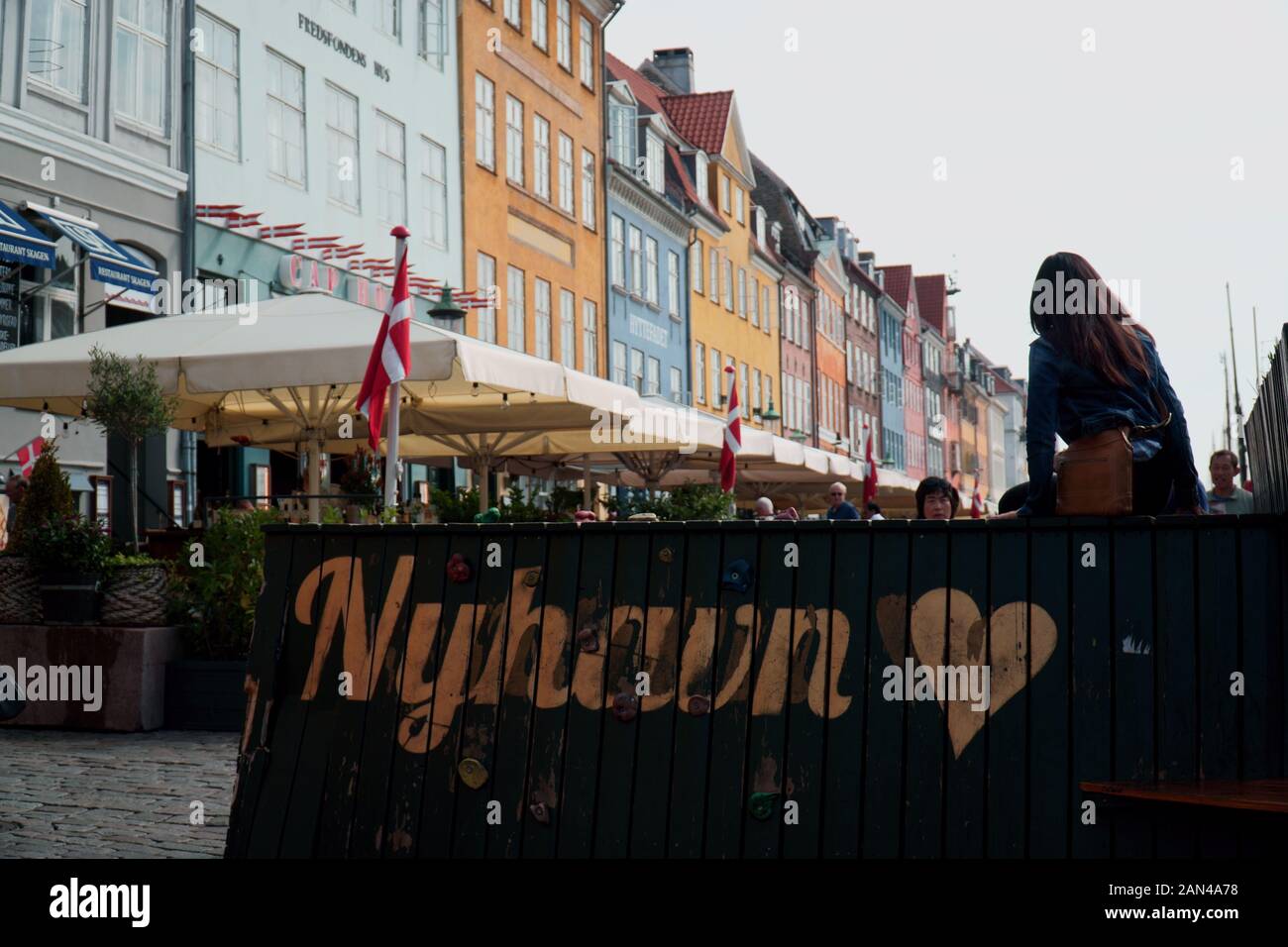 Person poses on a sign in the popular tourist area of Nyhavn, Copenhagen Stock Photo