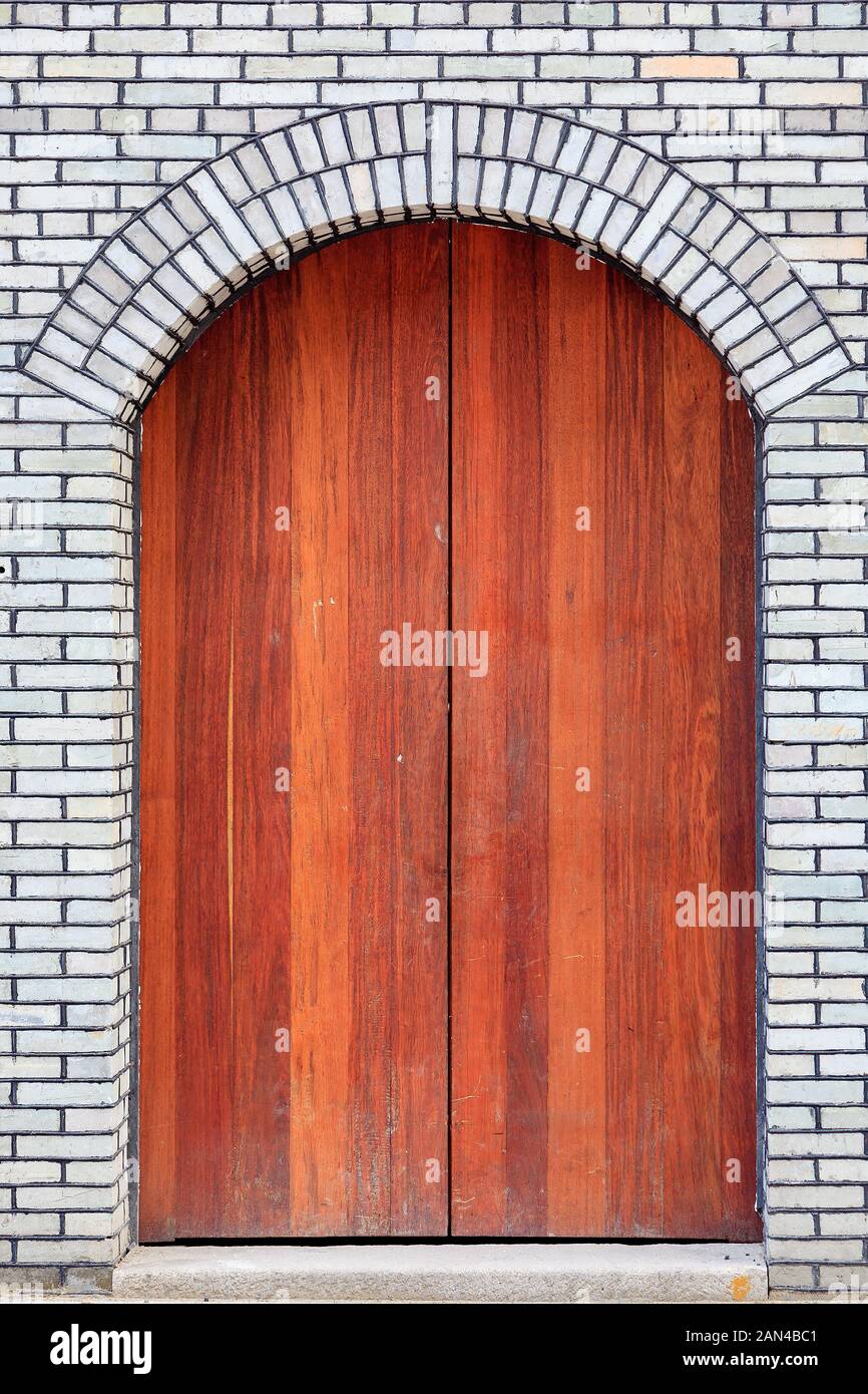 The traditional  wooden arched door and brick wall,which has the style of typical architecture of southern China in the Late Qing Dynasty . Three lane Stock Photo