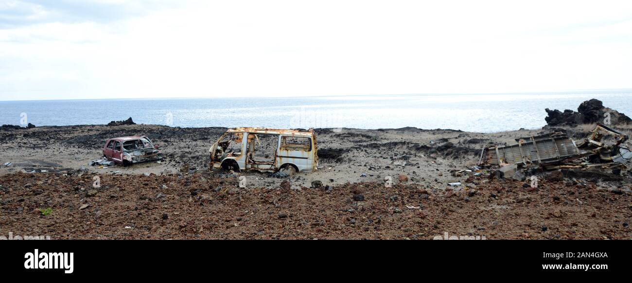 Old car bodies that got destroyed during bad accidents lay along the roads of Grande Comore, Comoros. Stock Photo