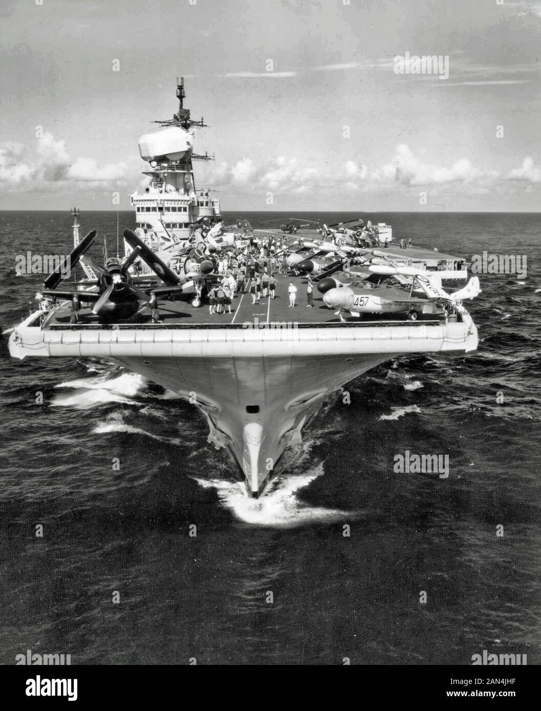 Bow view of the British Royal Navy aircraft carrier HMS Victorious (R38) operating off Norfolk, Virginia (USA), between 15 and 20 July 1959. On deck are several planes of Victorious´ air group: a Douglas Skyraider AEW.1 of 849 Naval Air Squadron, five de Havilland Sea Venom fighters of 893 NAS, two Supermarine Scimtar fighters of 803 NAS, and a Westland Dragnonfly HR.5 of Ships Flight 1 (Search and Rescue). Also on deck are serveral U.S. Navy aircraft (starboard bow): A McDonnell F3H-2 Demon of Fighter Squadron 31 (VF-31) 'Tomcatters', and a barely visible Vought F8U-1E Crusader (BuNo 145544) Stock Photo