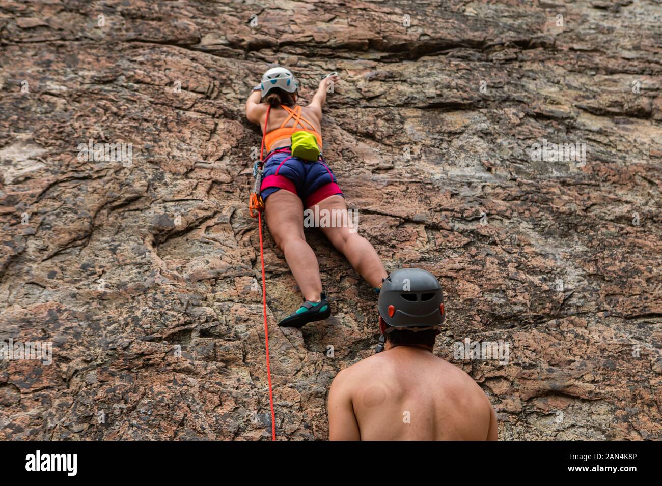Top rope climbing in action as a female climber is seen securing belay ...