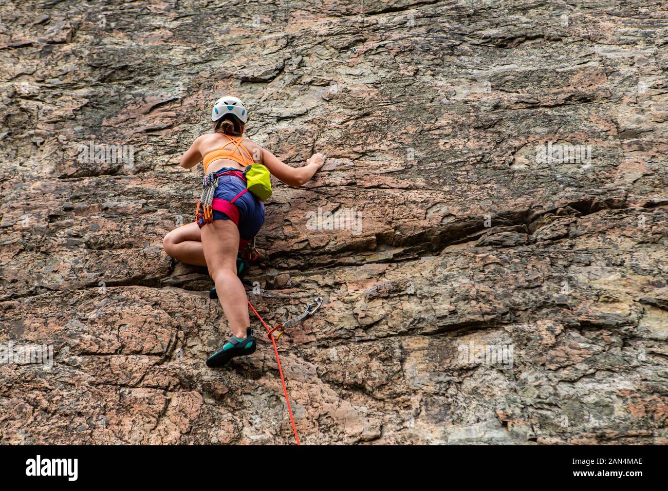 A woman is seen wearing a safety harness and helmet during belaying, a
