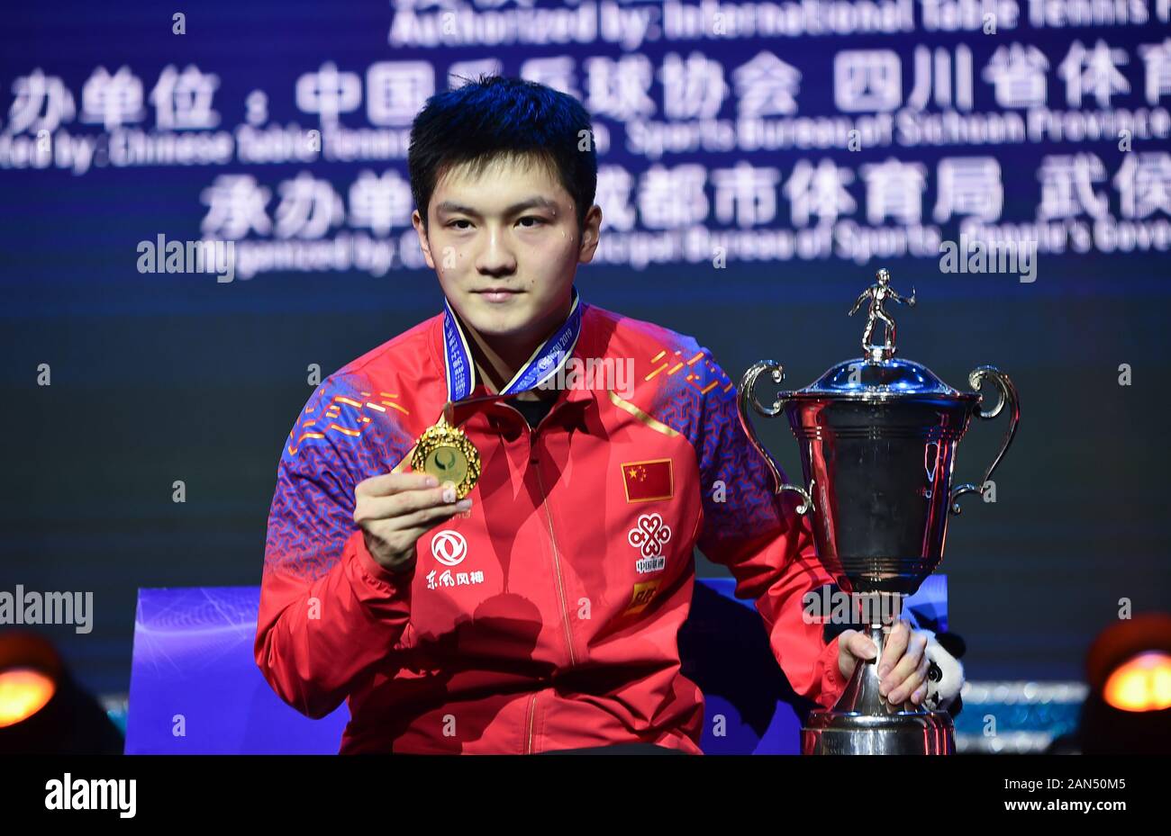 Fan Zhendong of China shows the medal and cup after winning the first