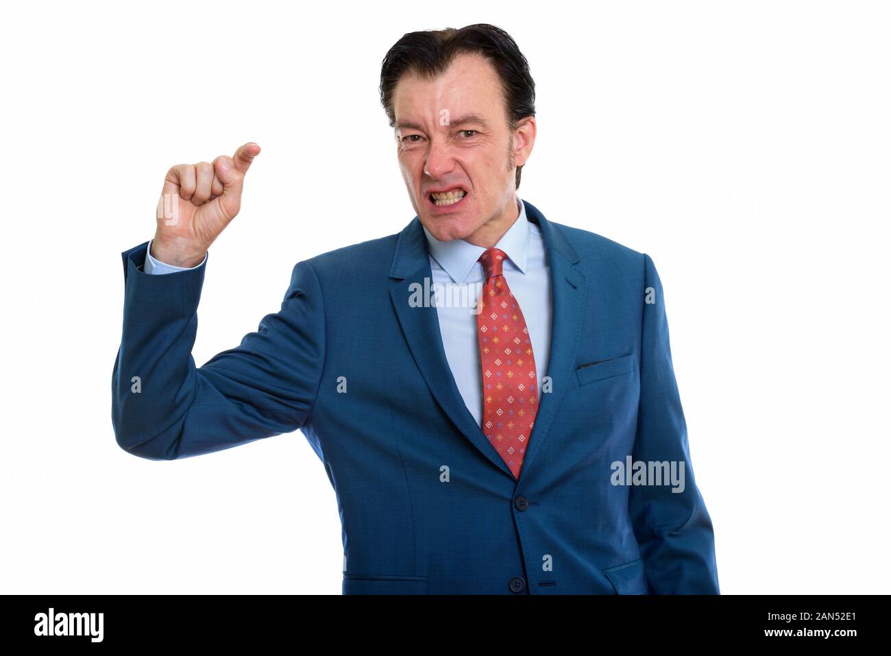Studio shot of mature businessman looking furious while pointing finger ...