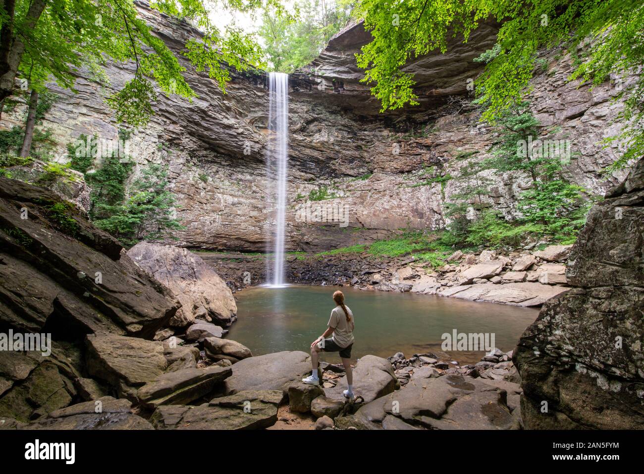 Woman standing and admiring the majestic Ozone Falls in Crossville, Tennessee which plunges 110 feet over a sandstone rock into a deep pool. Stock Photo