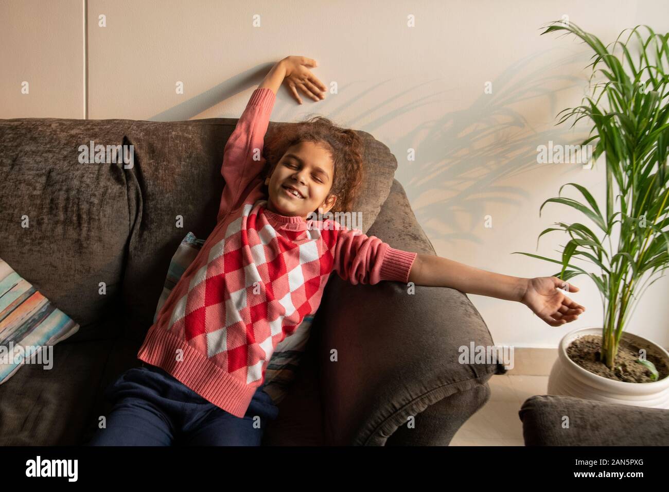 Young girl stretching away her tiredness on the couch at home. (Children) Stock Photo